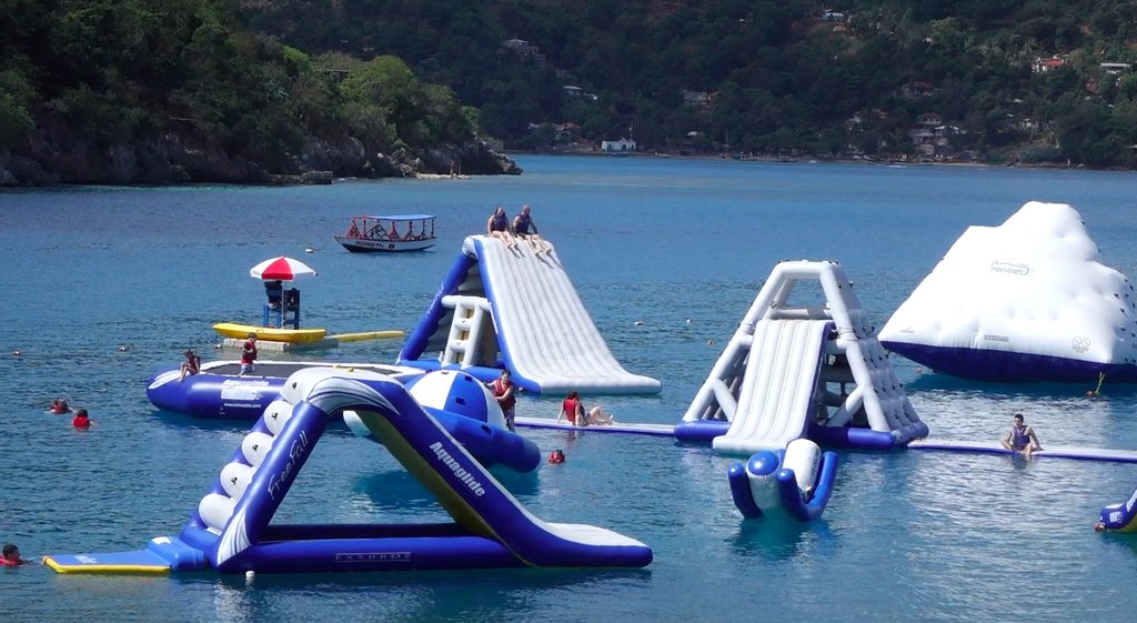 Inflatable water park playground with blue and white slides in tropical bay