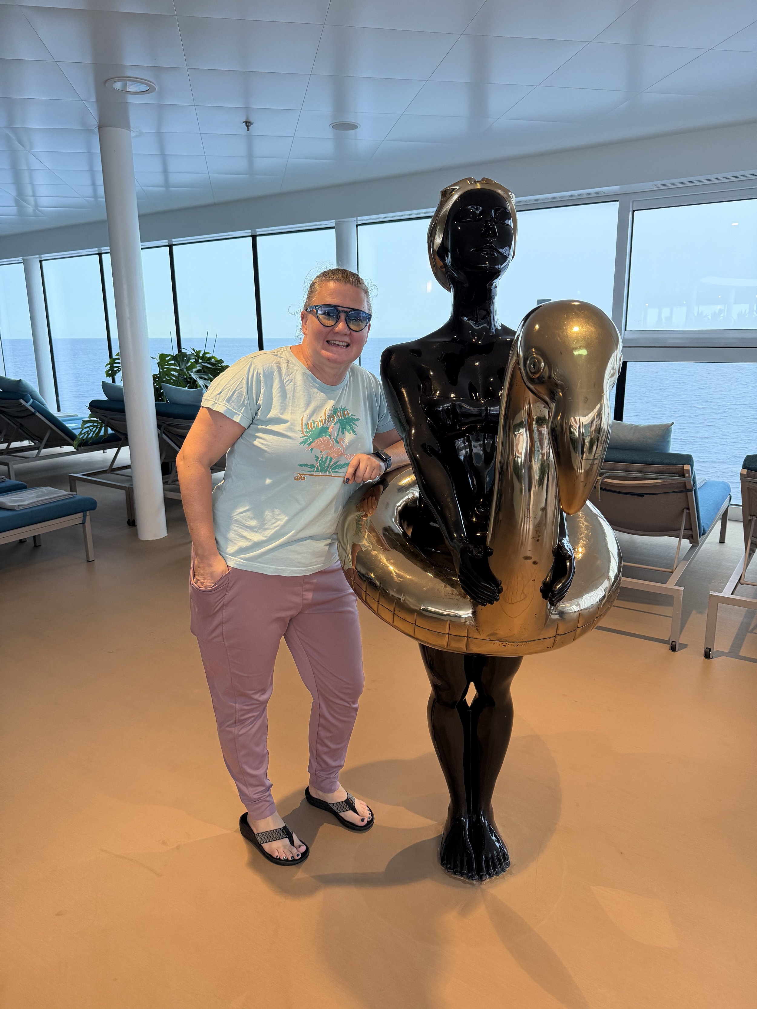 Person posing with decorative statues on cruise ship deck