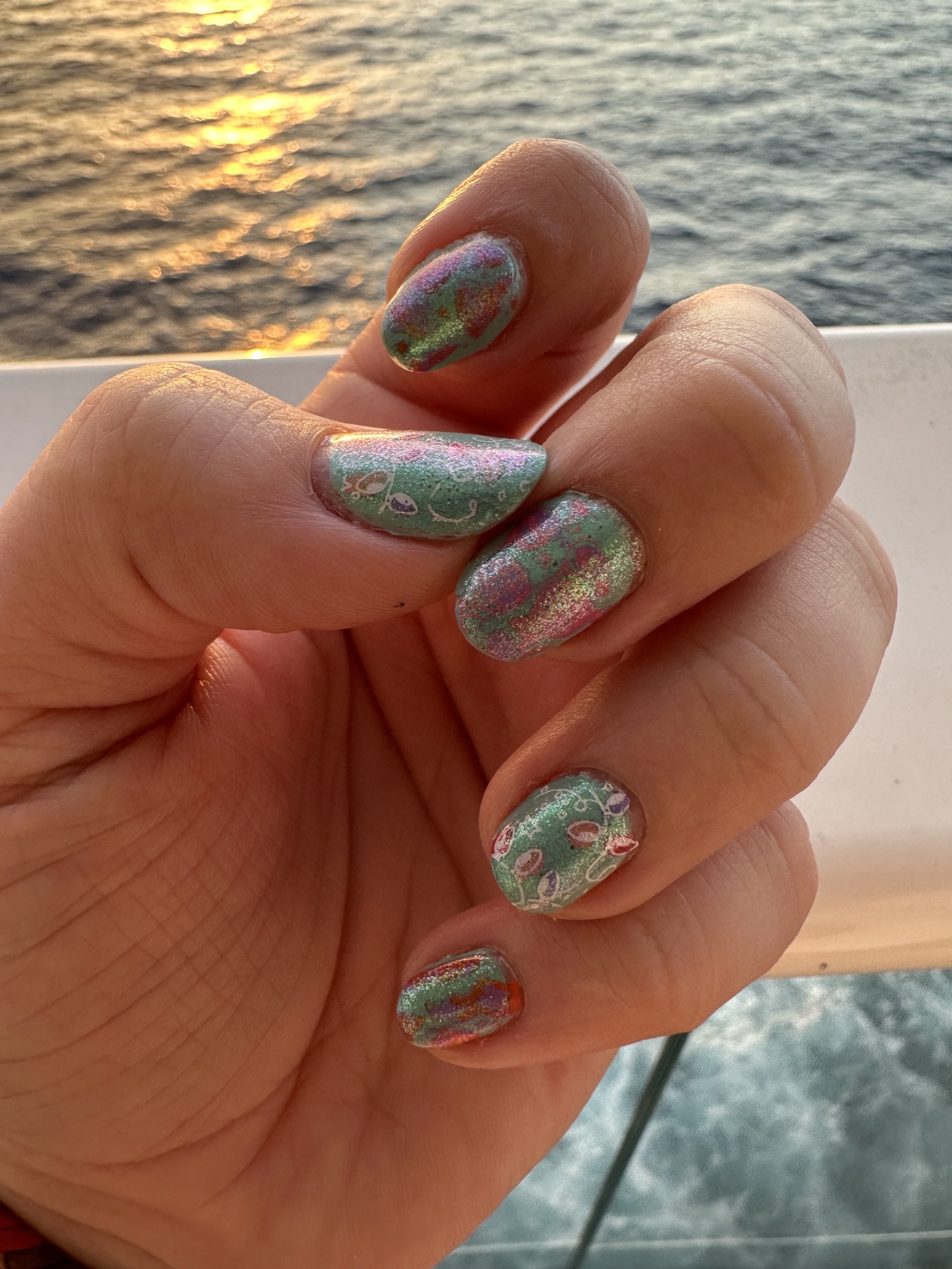 Colorful glitter nail art displayed on cruise ship deck at sea