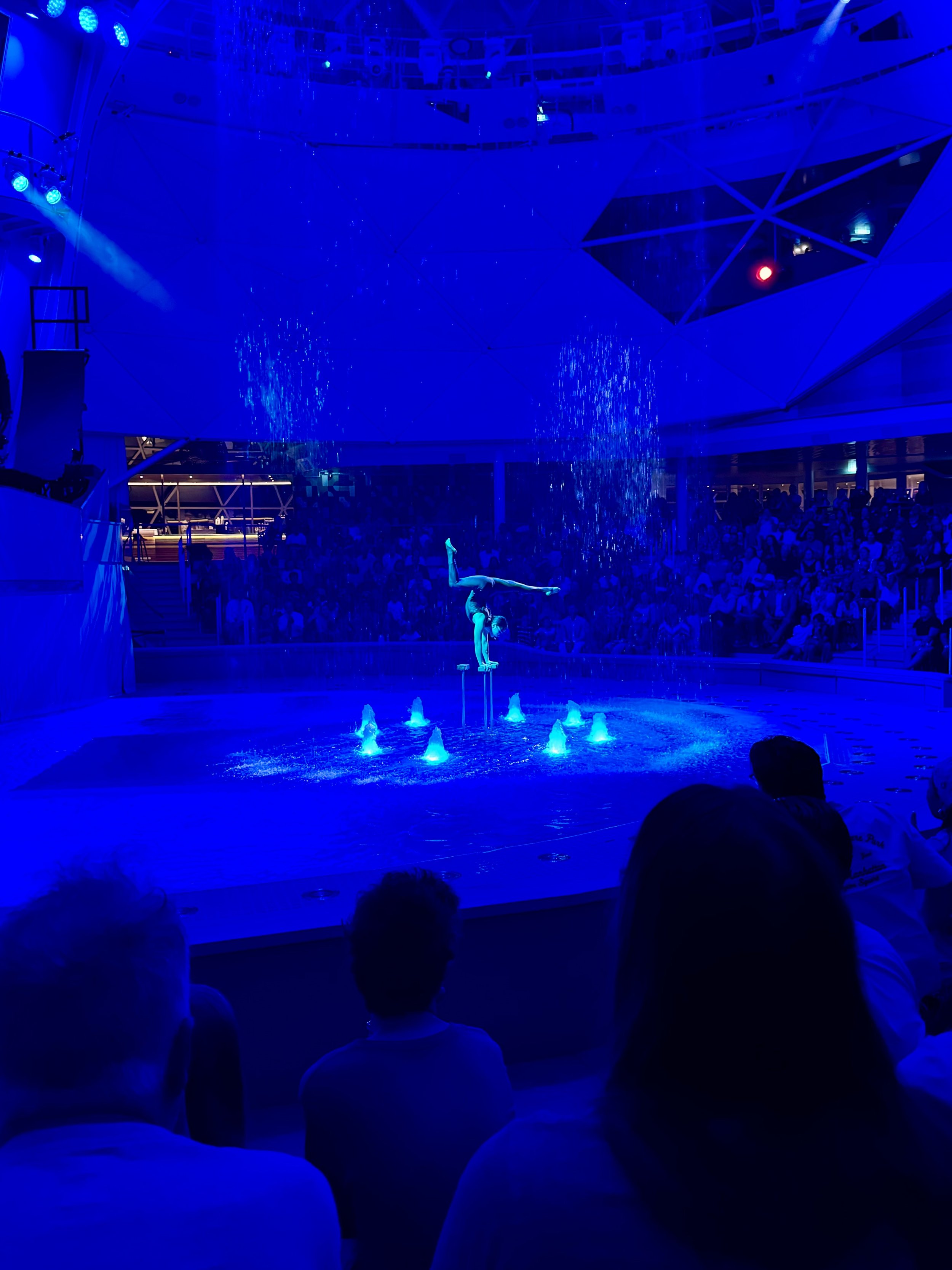 Acrobat performs handstand on illuminated circus stage with audience