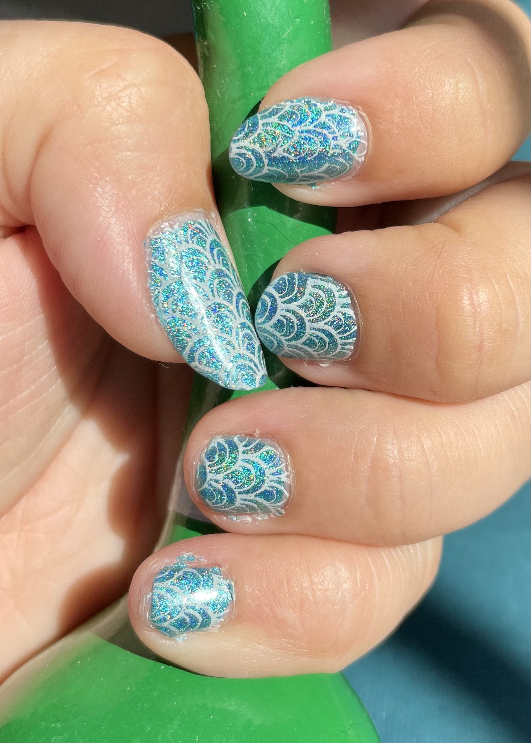 Turquoise glitter nail art with intricate lace pattern design