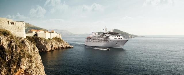 Large cruise ship anchored near Mediterranean coastal fortress ruins